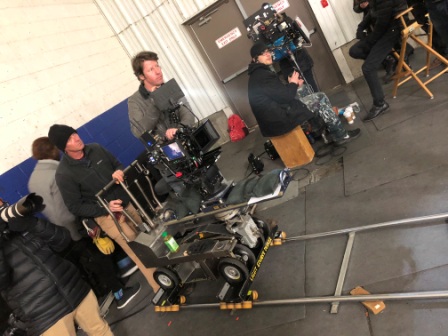 Grip and camera crew setting up a Fisher dolly track and camera rig for a production shoot